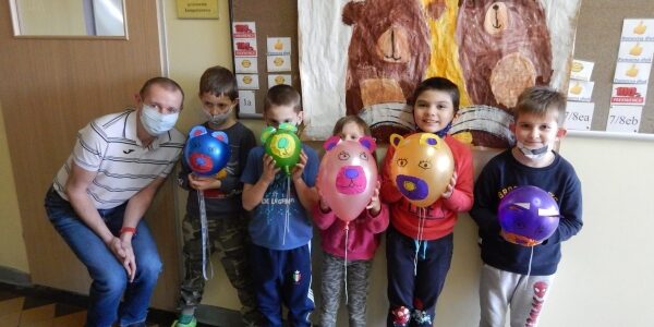 Uczniowie klasy 1a wraz z nauczycielem z własnoręcznie zrobionymi balonami przypominającymi misia.
