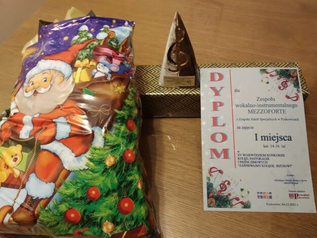 Dyplom, statuetka i reklamówka z postacią Mikołaja z prezentami.