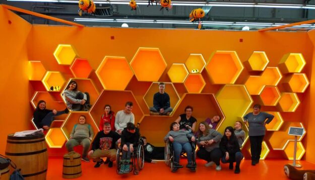 uczniowie wraz z nauczycielami siedzą w makiecie plastra miodu