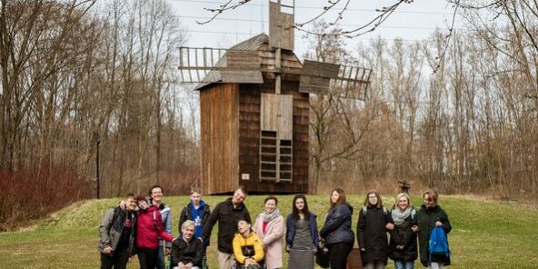 uczestnicy wycieczki stoją na tle starego młyna