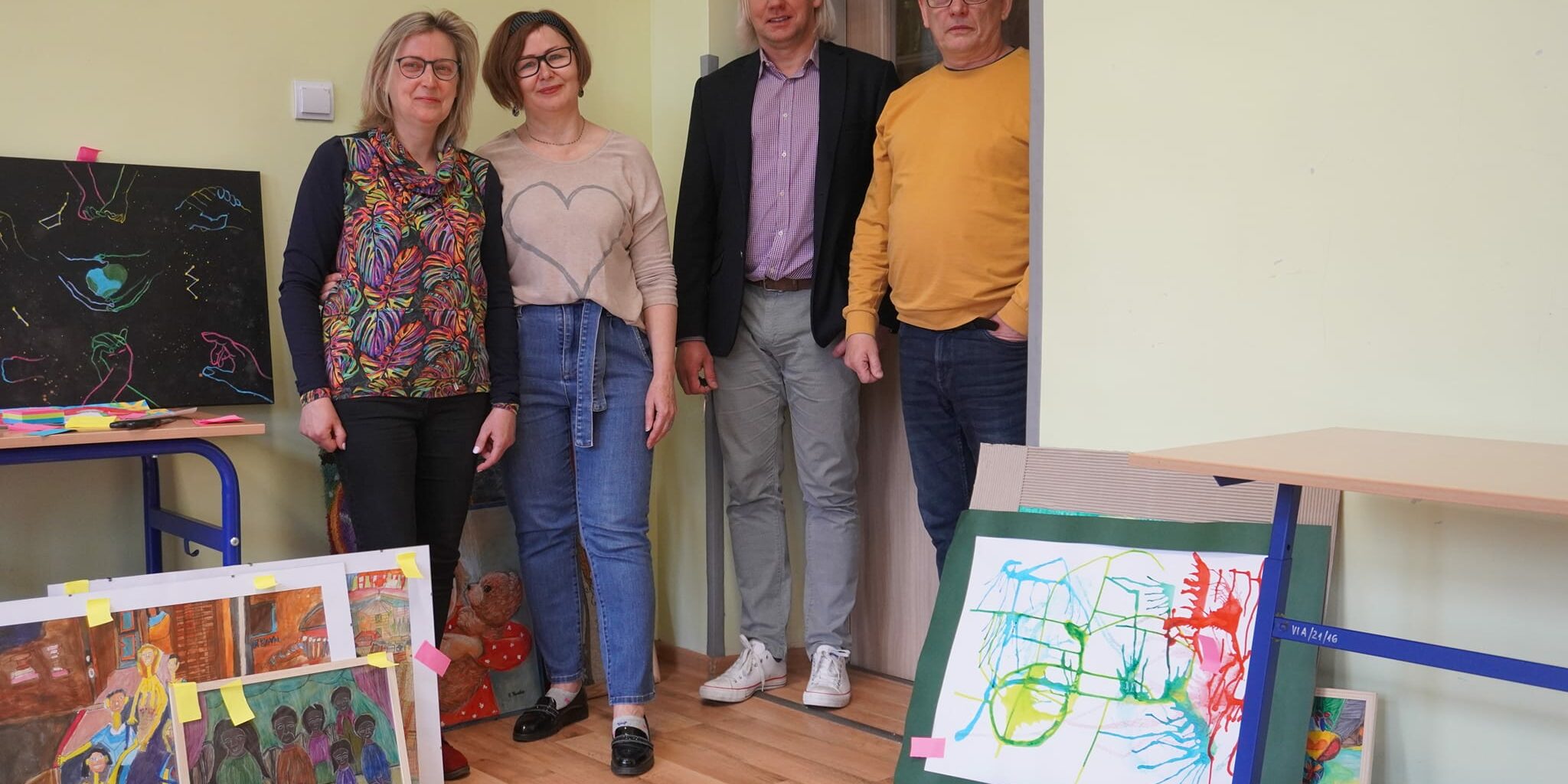 Jury w pełnym składzie stoi na tle nadesłanych prac