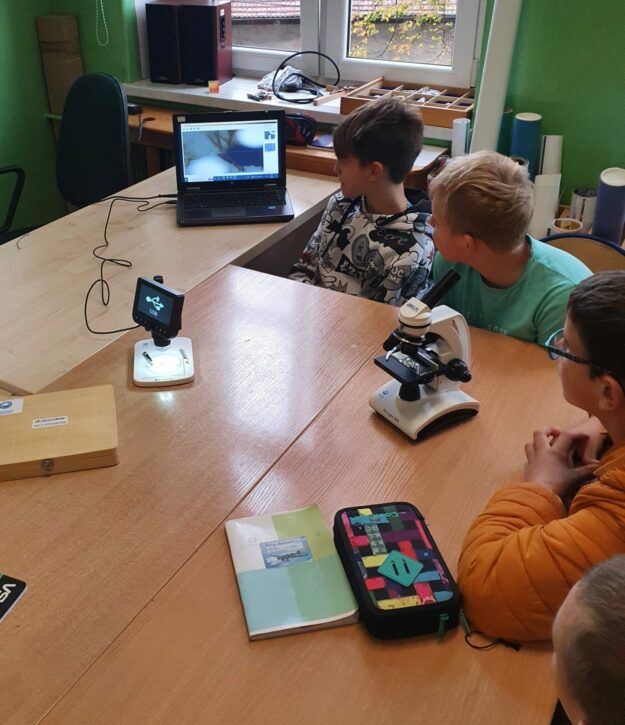 uczniowie obserwują na ekranie laptopa widok preparatu z mikroskopu.