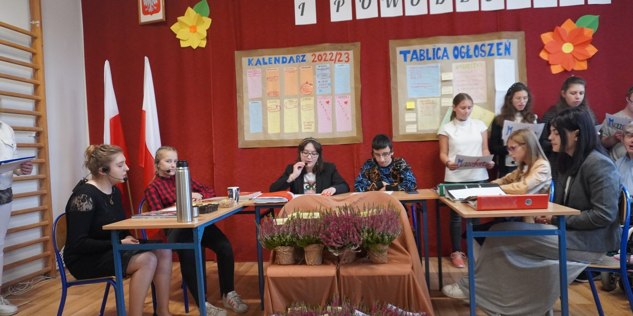 Uczniowie występujący na akademii na tle dekoracji