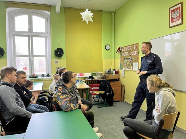 policjant w sali lekcyjnej mówi do zgromadzonych tam uczniów.
