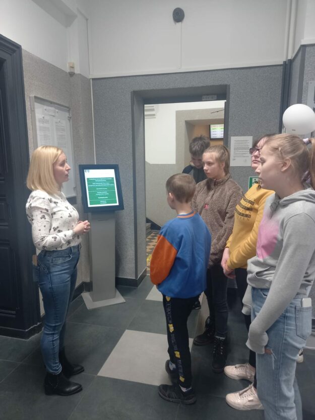uczniowie na korytarzu urzędu pracy słuchają prowadzącej zajęcia