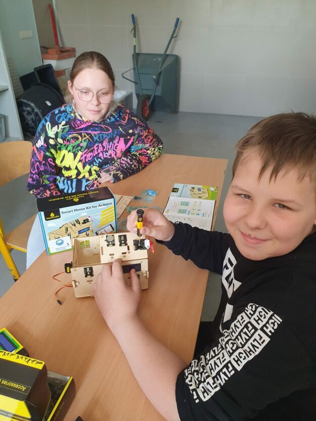 Uczeń i uczennica składają model domu
