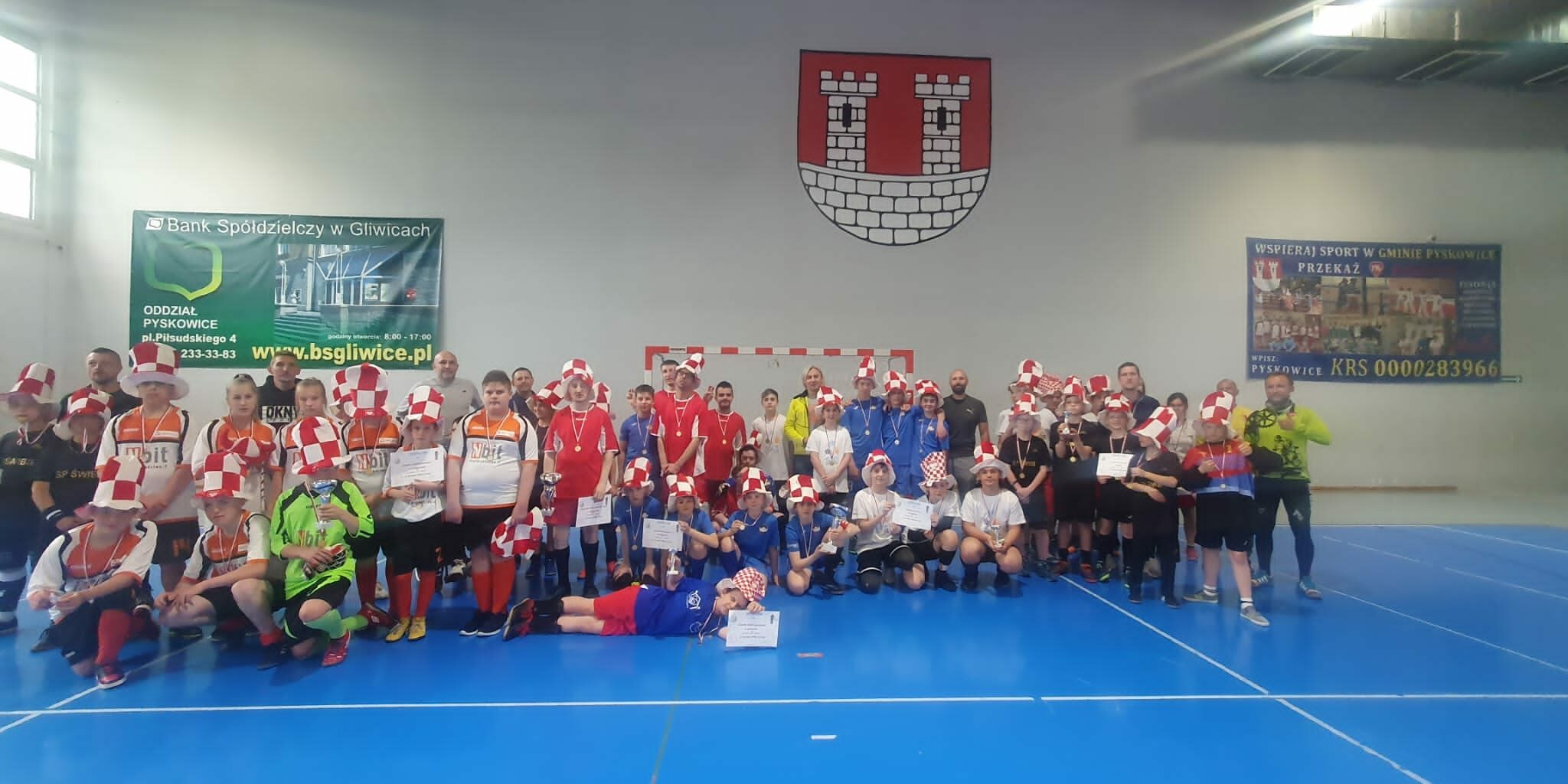 wszyscy uczestnicy turnieju stoją na tle herbu Pyskowic do pamiątkowego zdjęcia