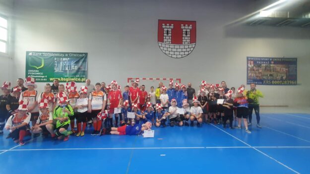 wszyscy uczestnicy turnieju stoją na tle herbu Pyskowic do pamiątkowego zdjęcia