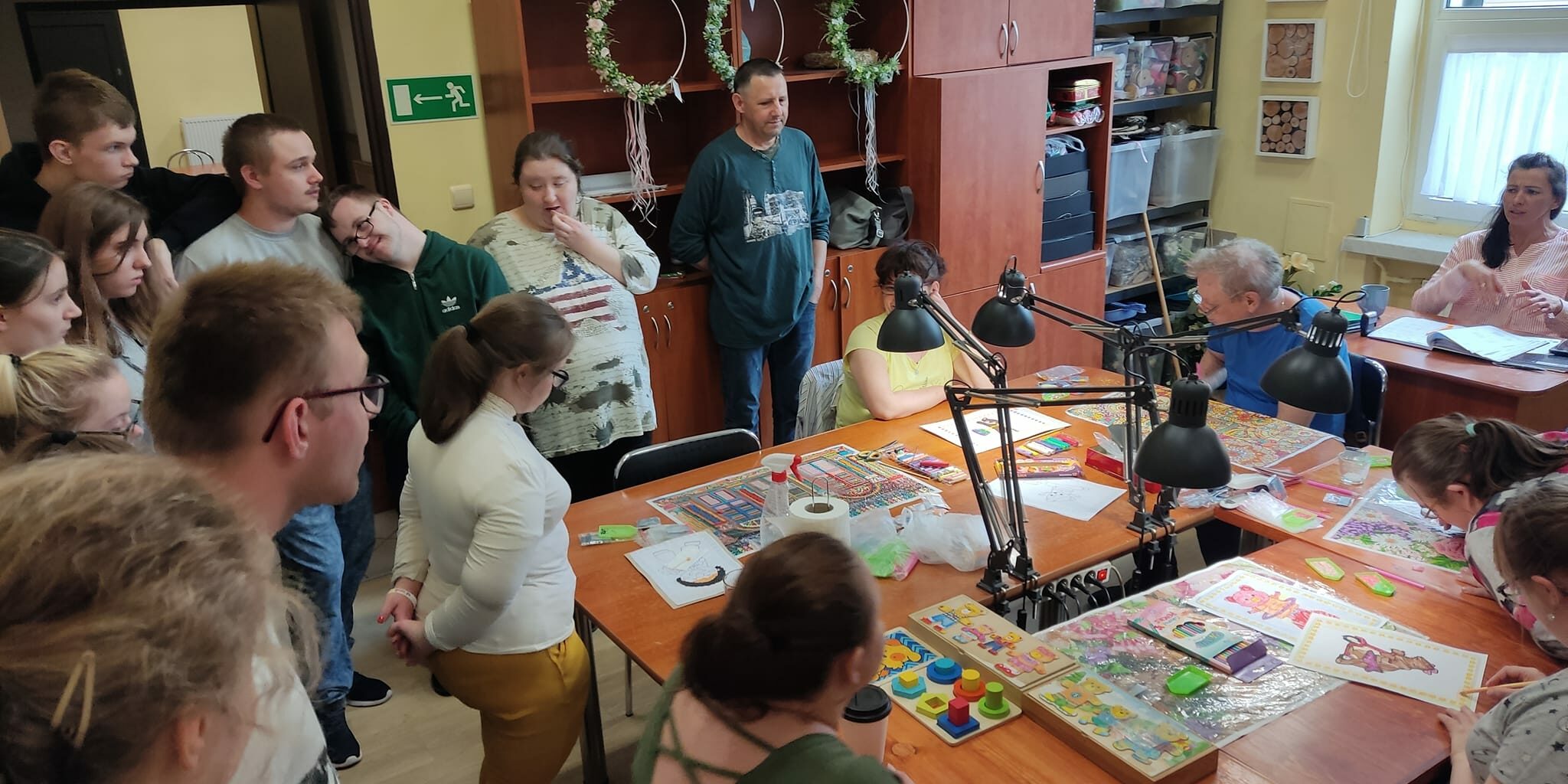 uczestnicy wycieczki obserwują pracę w pracowni zdobniczej, wyklejanie haftem diamentowym