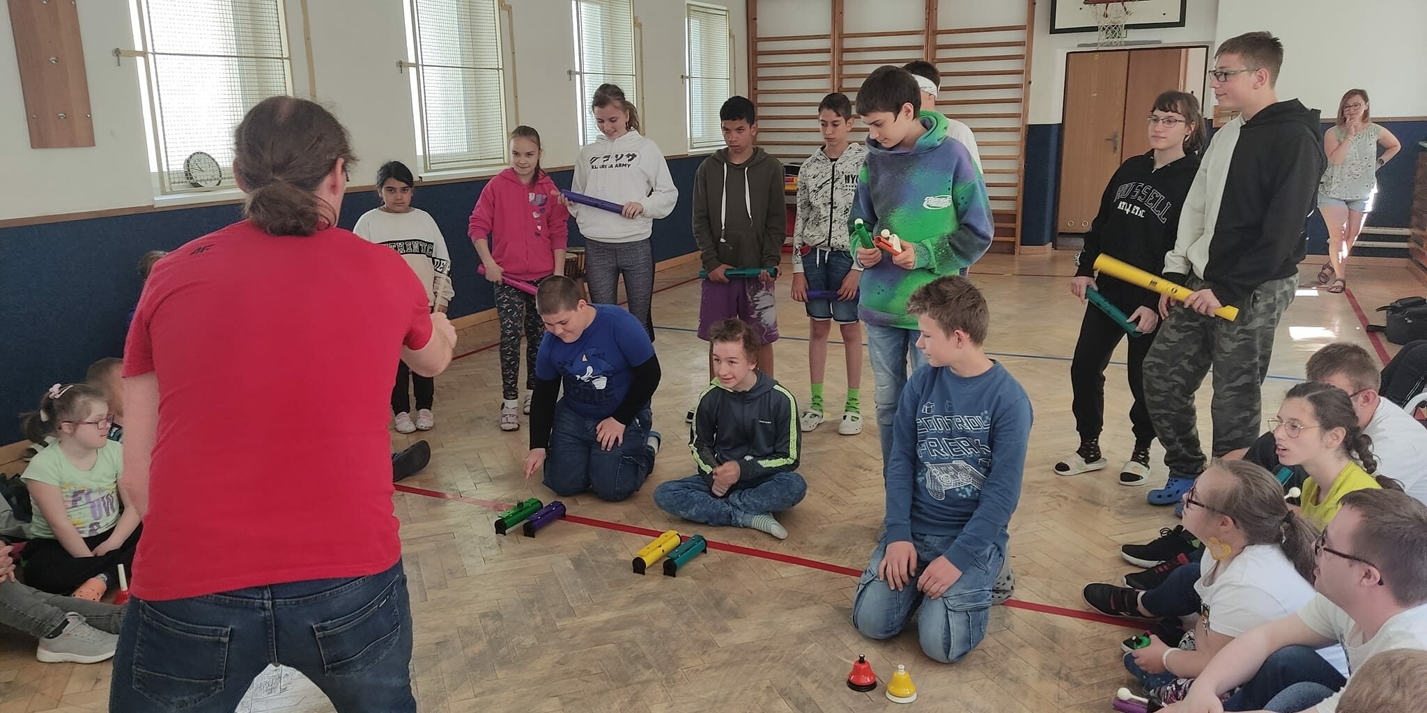 nauczyciel dyryguje uczniami, którzy grają na różnych instrumentach