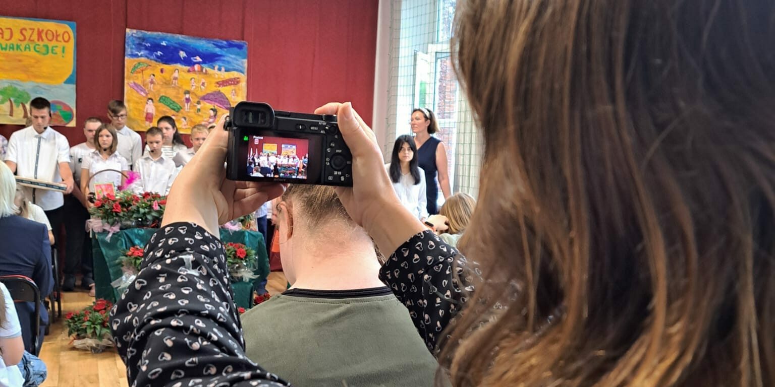 nauczycielka wykonuje zdjęcia z akademii aparatem fotograficznym