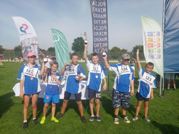 uczniowie stoją w grupie i prezentują swoje medale i puchary