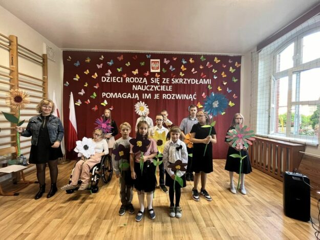 uczniowie występujący w akademii stoją na tle dekoracji