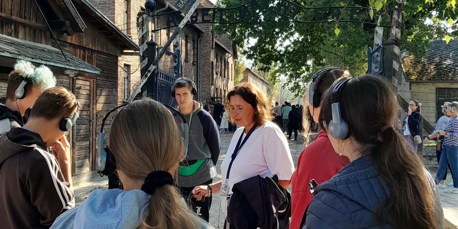 uczniowie stoją przed bramą wejściową obozu koncentracyjnego w Oświęcimiu