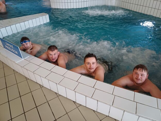 czterech uczniów leży w wodnym jacuzzi