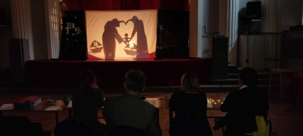 cienie rzucone na białe płótno przedstawiające serce i siedzące na nim dziecko