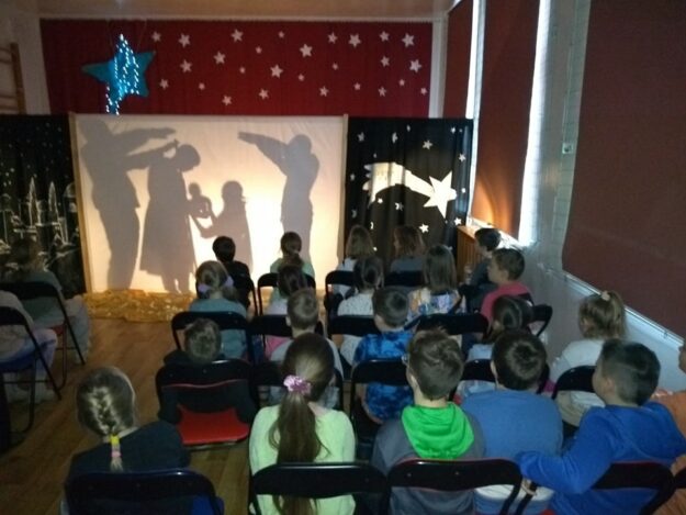 zaproszeni uczniowie oglądają jasełka w konwencji teatru cieni