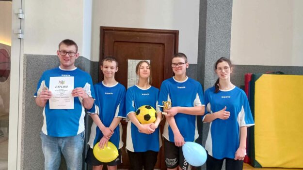 uczniowie stoją w szeregu prezentując dyplom puchar i piłkę