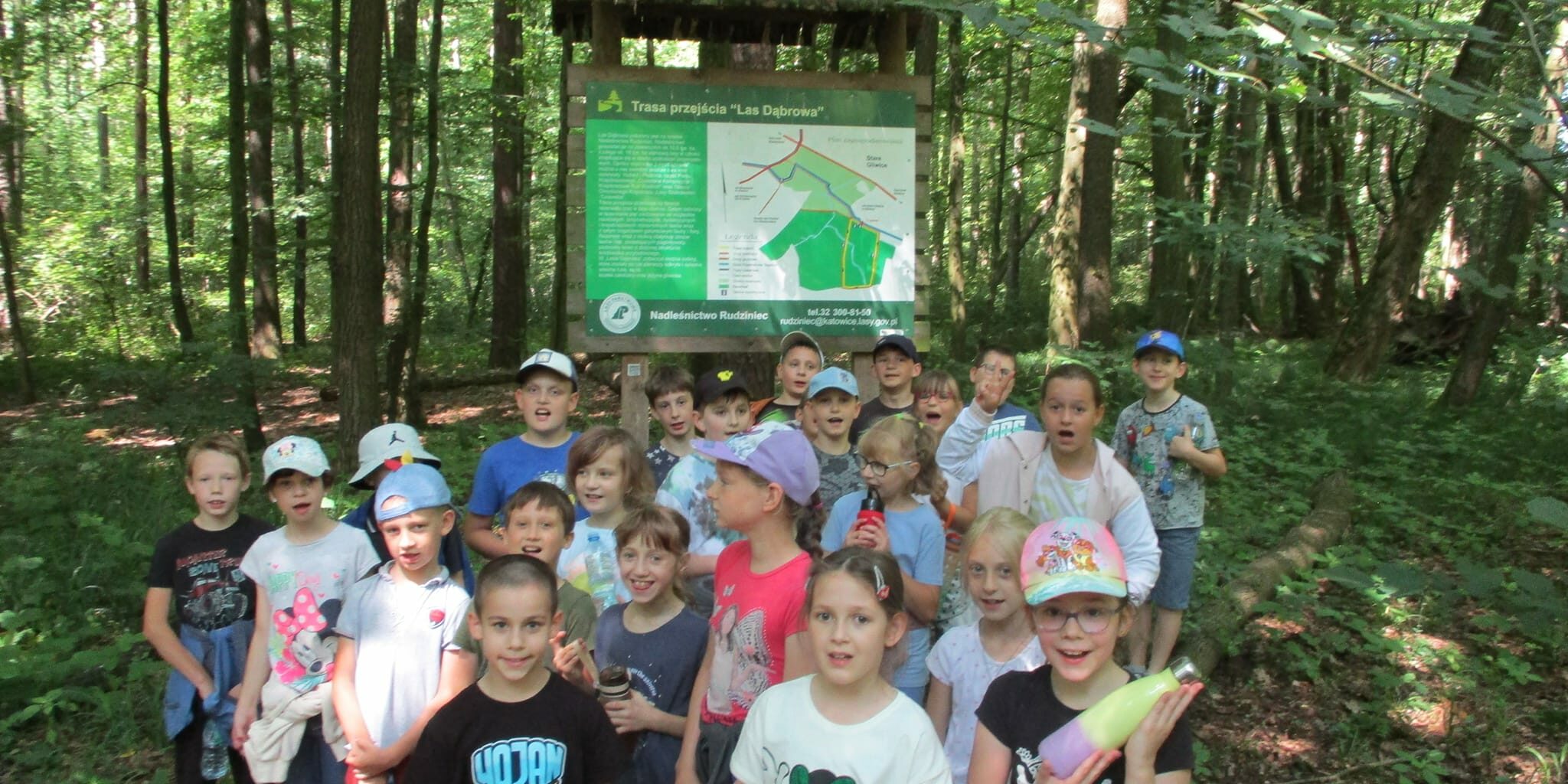 uczestnicy wycieczki stoją na tle lasu