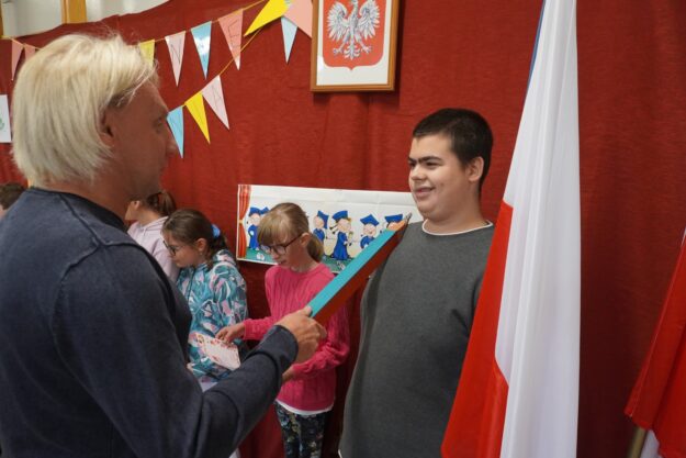 dyrektor szkoły pasuje nowego ucznia ołówkiem