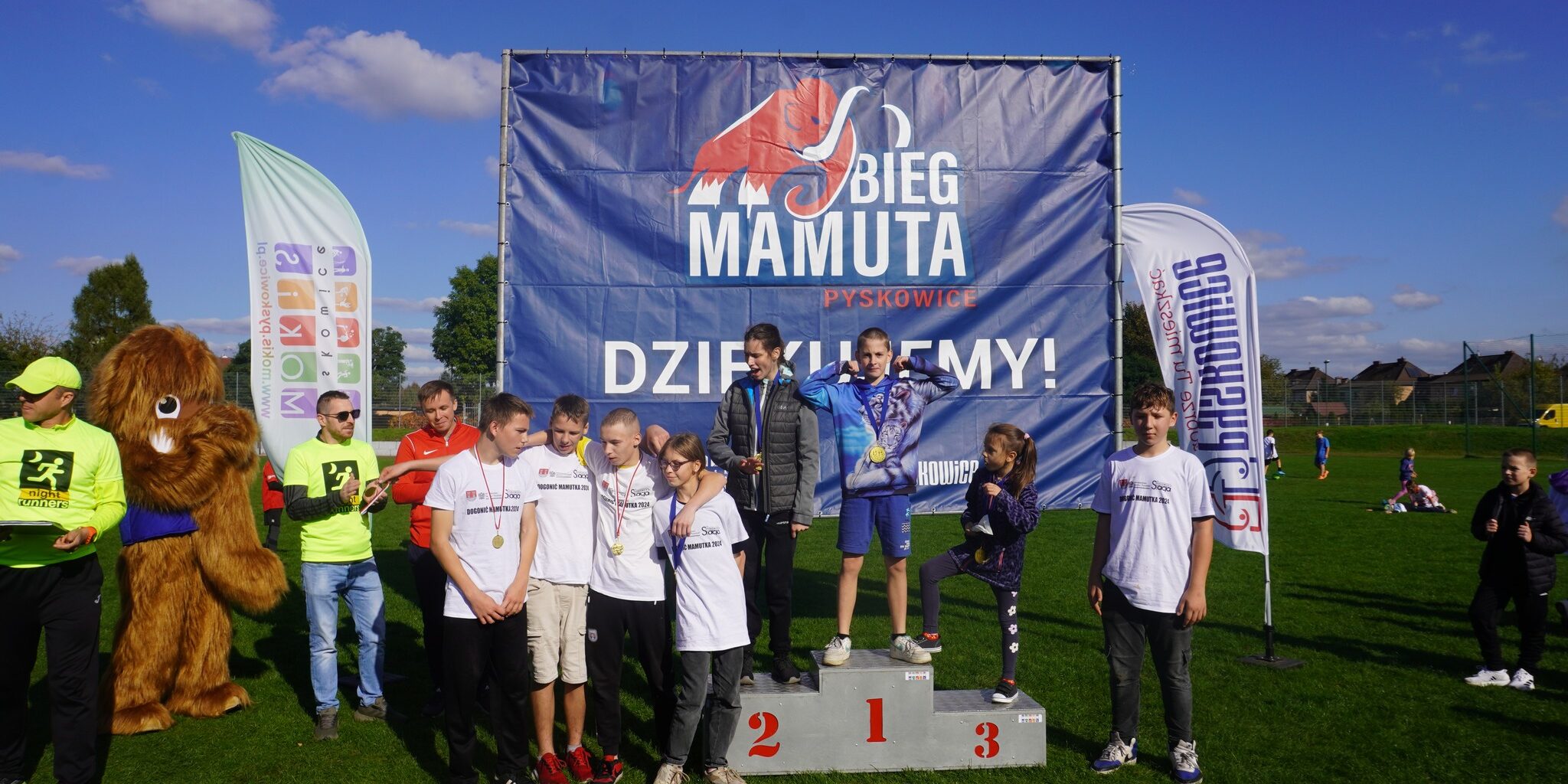 uczniowie stoją na podium i obok niego