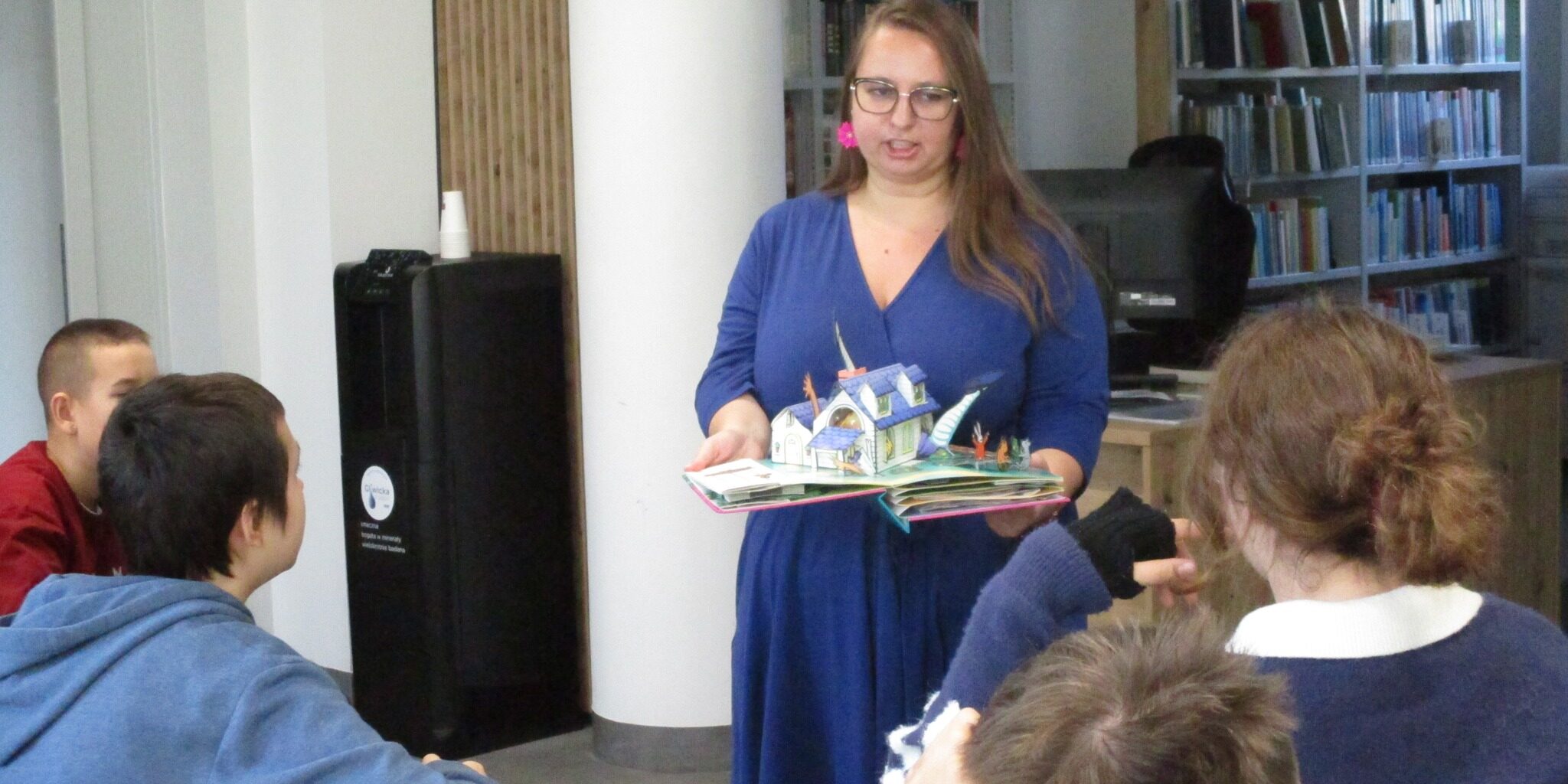 kobieta prezentuje uczniom rozkładana książkę